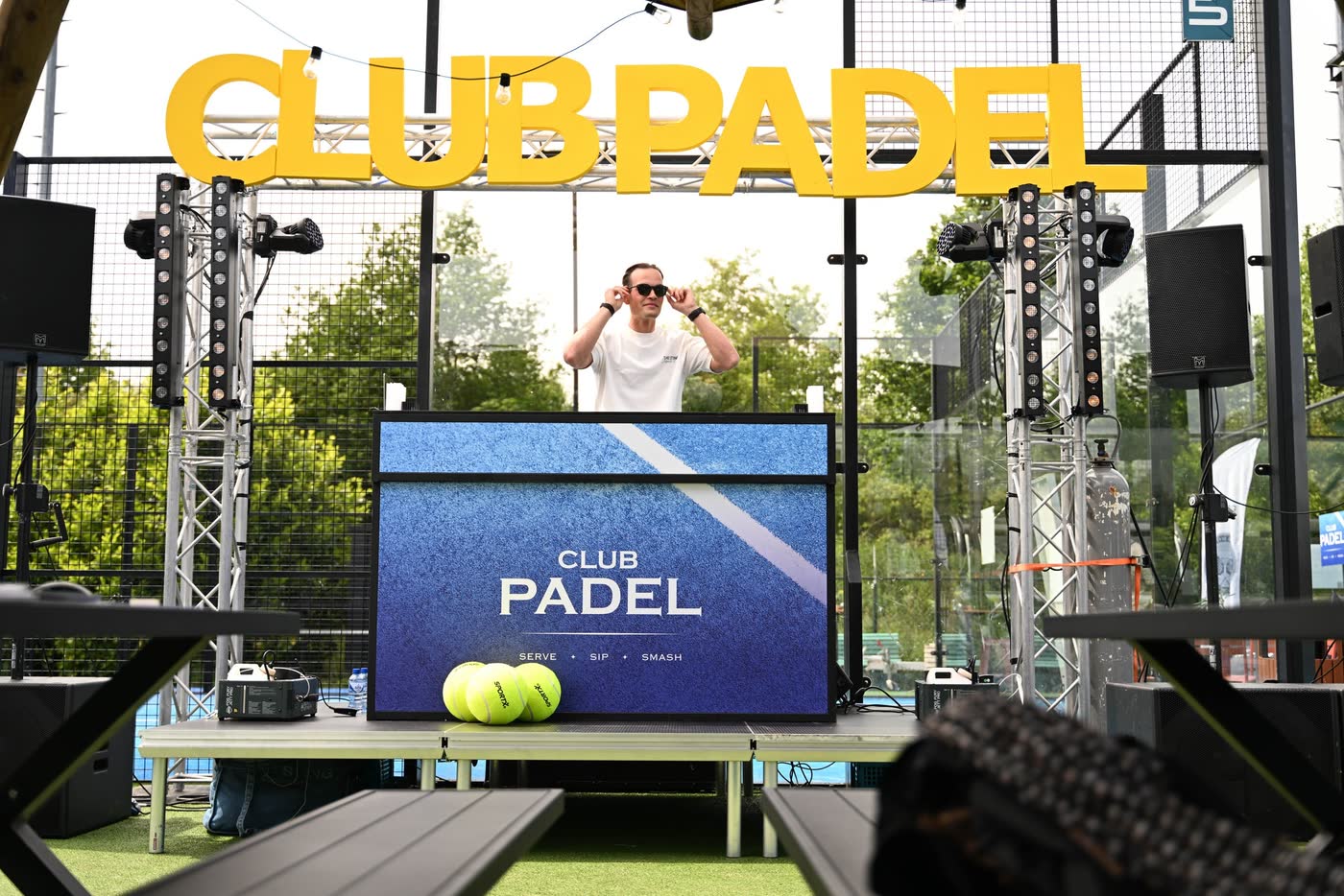 DJ achter een Club Padel-booth onder grote gele Club Padel-letters